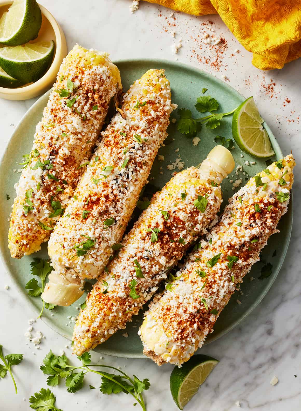 Elote on plate with lime wedges and cilantro